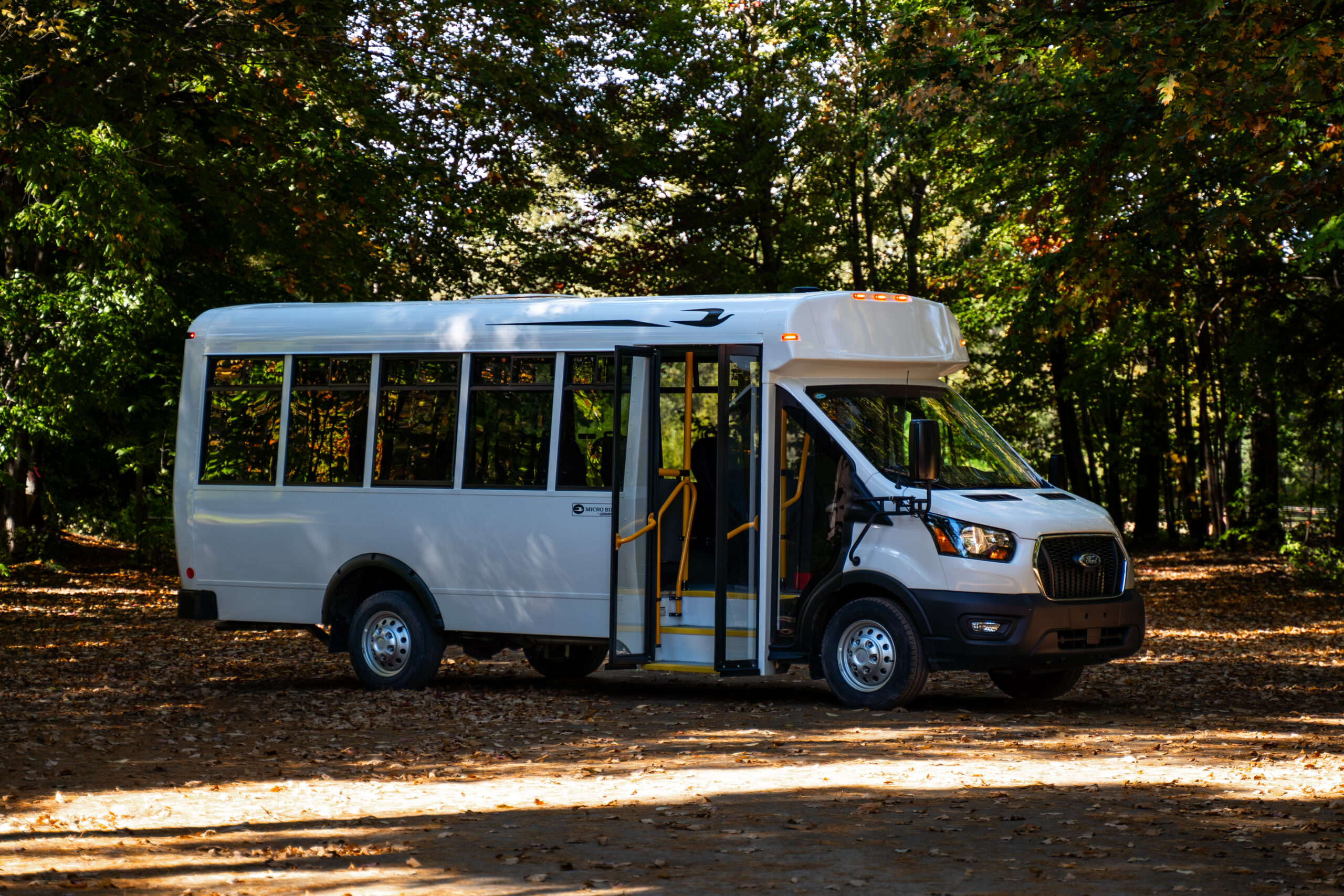 Micro Bird CT-Series commercial bus on a tree-lined road during fall